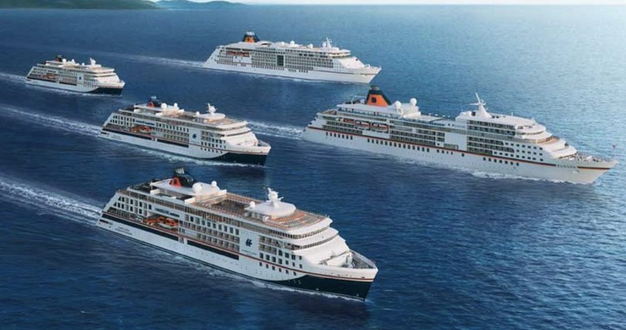 A fleet of cruise ships of different sizes sailing side by side at sea