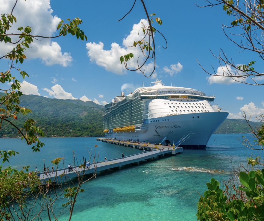 Harmony of the Seas docked at a pier in Jamaica, with turquoise water in the foreground